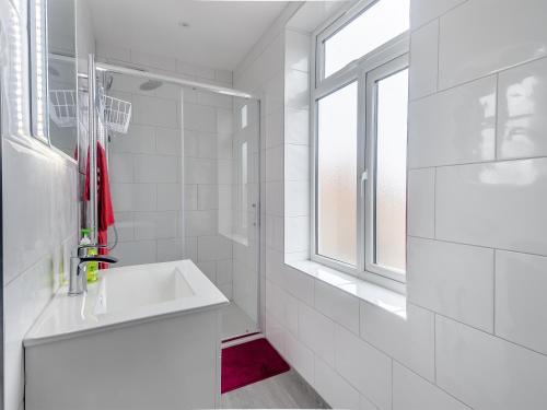 a white bathroom with a sink and a window at No, 2 - Uk46743 in Cromer