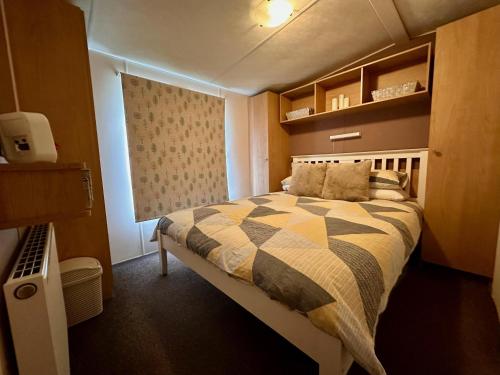 1 dormitorio con cama y ventana. en Great Caravan With Wifi And Decking At Dovercourt Holiday Park Ref 44006c en Great Oakley