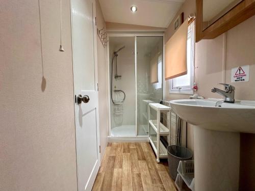 y baño con lavabo y ducha. en Great Caravan With Wifi And Decking At Dovercourt Holiday Park Ref 44006c en Great Oakley