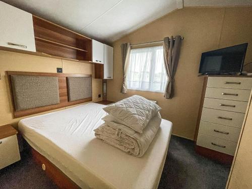 a small bedroom with a bed and a tv at Lovely Caravan With Decking And Free Wifi At Valley Farm, Essex Ref 46610v in Great Clacton
