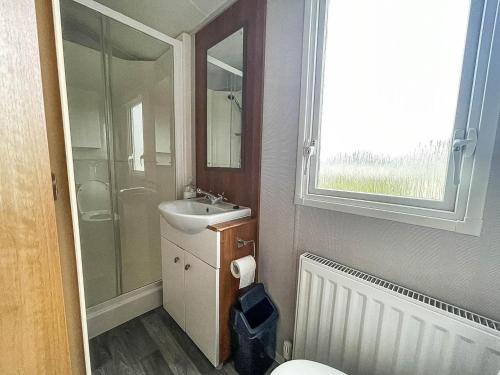 uma casa de banho com um WC, um lavatório e um espelho. em Lovely Caravan With Decking And Free Wifi At Valley Farm, Essex Ref 46610v em Great Clacton
