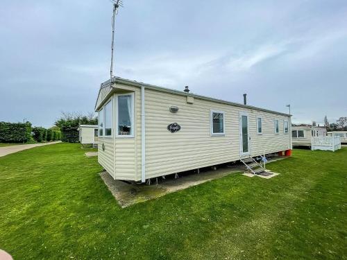 a white tiny house sitting on a grass field at Lovely 8 Berth Caravan At Breydon Water Park, Nearby Norfolk Broads Ref 10111b in Belton