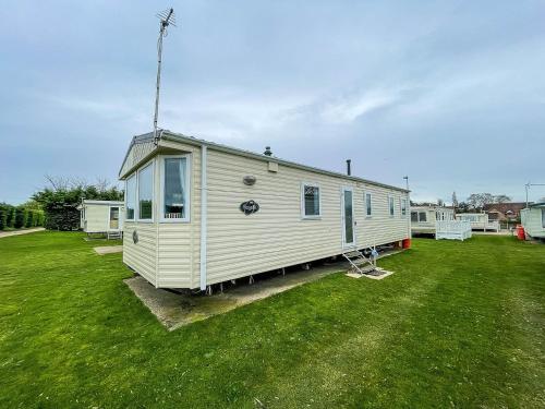 a white tiny house sitting on a grass field at Lovely 8 Berth Caravan At Breydon Water Park, Nearby Norfolk Broads Ref 10111b in Belton