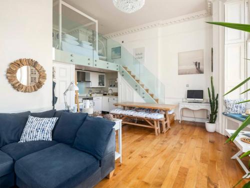 un soggiorno con divano blu e scala di The Little Beach House a Brighton & Hove