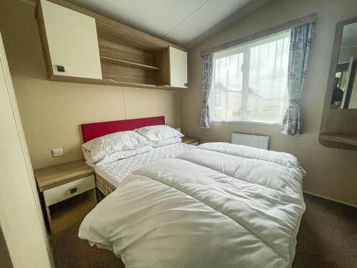 two beds in a small room with a window at Modern 6 Berth Caravan With Free Wifi Nearby Pakefield Beach Ref 68028cr in Lowestoft