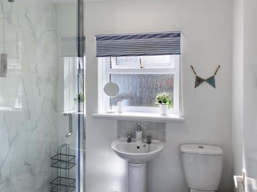 baño con lavabo y aseo y ventana en Kirnan Cottage en Kilmichael Glassary