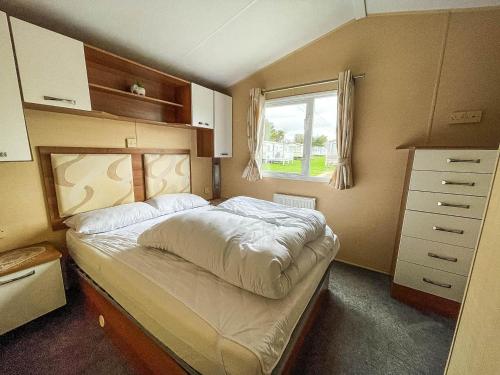 a small bedroom with a bed with a window at Wonderful 8 Berth Caravan At Valley Farm Nearby Clacton-on-sea Ref 46396v in Great Clacton