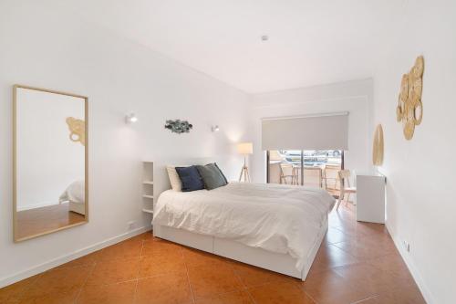 a white bedroom with a bed and a mirror at Albufeira Haven 103 in Albufeira