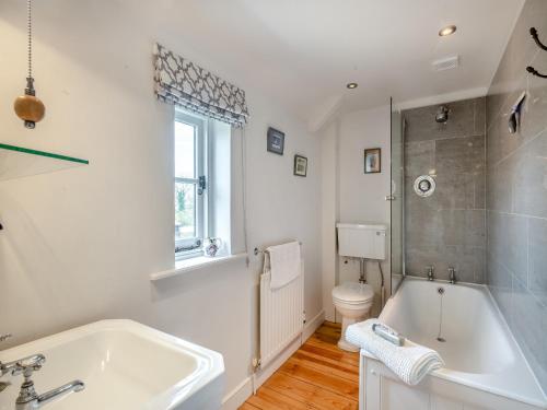 a white bathroom with a tub and a toilet at Swallow Cottages, No, 2 - Uk46810 in Thurgarton