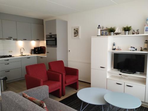 a living room with two red chairs and a kitchen at BRANDING Bed by the Sea in Westkapelle
