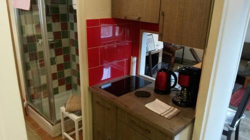 - une petite cuisine avec un évier et des placards rouges dans l'établissement La Petite Fugue, à Honfleur