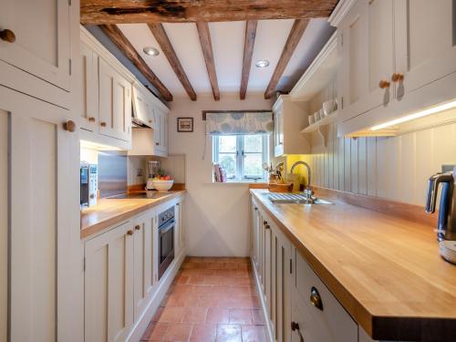 a kitchen with white cabinets and a wooden counter top at Swallow Cottages, No 1 - Uk46811 in Thurgarton