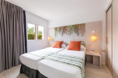 een slaapkamer met een groot wit bed met oranje kussens bij Palm Garden in Port d'Alcudia