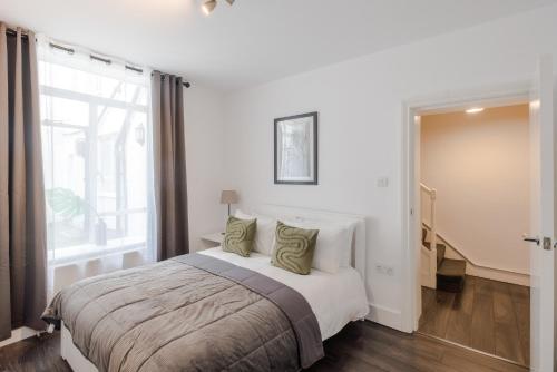 a white bedroom with a large bed and a window at Gloucester Place/Marylebone Apartments in London