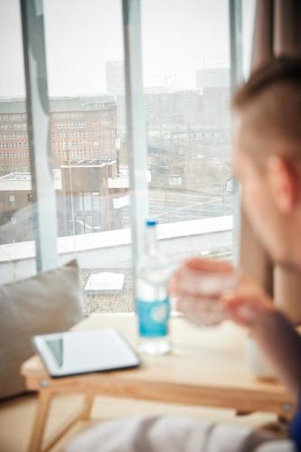 a person sitting at a table with a glass of water at Villa Viva - ein Haus das Brunnen baut in Hamburg