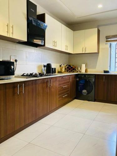 a large kitchen with wooden cabinets and a dishwasher at OD Cribs Luxury Apartment and On demand Car Service in Aso