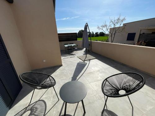 a patio with three chairs and an umbrella at CLOS ARIA NOVA in Lucciana