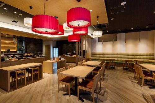 un restaurante con mesas, sillas y lámparas de araña rojas en Via Inn Hakataguchi Ekimae, en Fukuoka