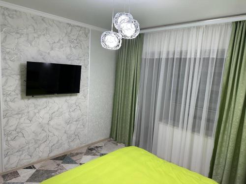 - une chambre avec une télévision à écran plat et un lit dans l'établissement 3х комнатная квартира, à Chimkent