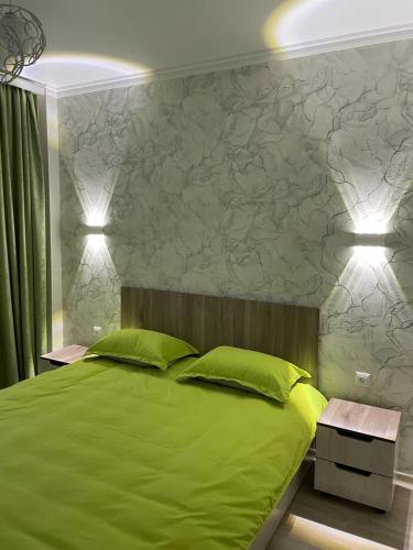 a bedroom with a green bed with two green pillows at 3х комнатная квартира in Shymkent