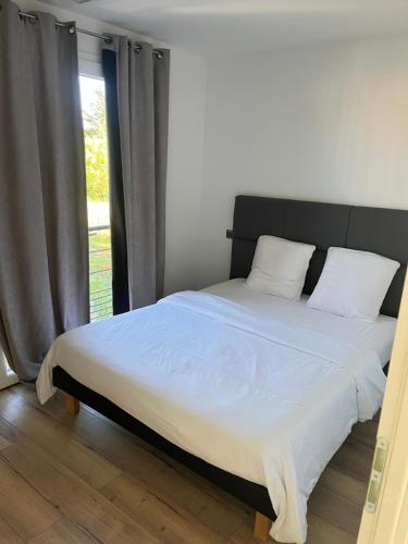 un lit dans une chambre avec une grande fenêtre dans l'établissement Mimosas résidence, à Juvignac