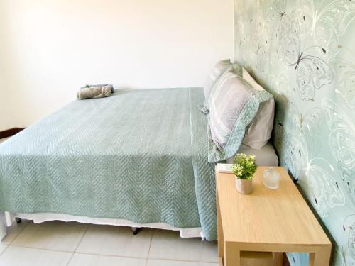 een slaapkamer met een bed en een houten tafel bij Ondas de Marina pé na areia - BAHIA in Lauro de Freitas