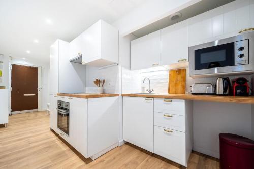 une cuisine blanche avec des armoires blanches et un micro-ondes dans l'établissement Le Patio de Juvénal, Beau T2, Patio, Centre Ville, à Montpellier