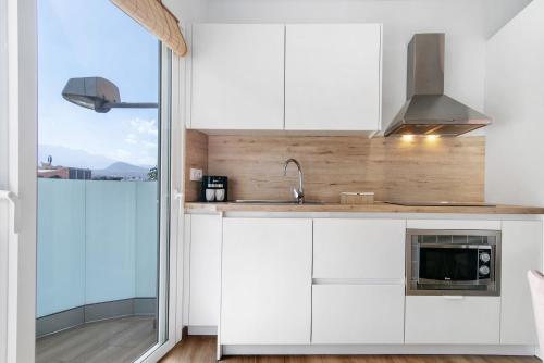 a kitchen with white cabinets and a sink and a window at Flamboyan 2 in Telde