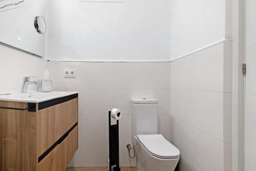 a white bathroom with a toilet and a sink at Flamboyan 2 in Telde