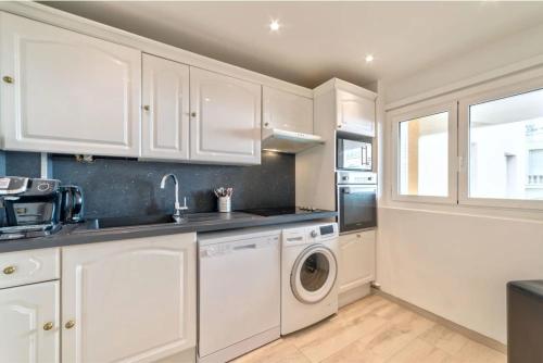 une cuisine avec des armoires blanches et une laveuse et une sécheuse dans l'établissement Agréable 3pièces Cannes Croisette, à Cannes