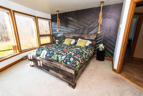 a bedroom with a bed in a room with windows at Luxury Mountain Mansion Huge Pool, Sauna, 7000sqft in Windham