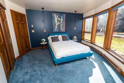 a blue bedroom with a bed and a large window at Luxury Mountain Mansion Huge Pool, Sauna, 7000sqft in Windham