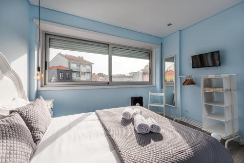 een blauwe slaapkamer met een bed met handdoeken erop bij GuestReady - Assuntos de recreio in Porto