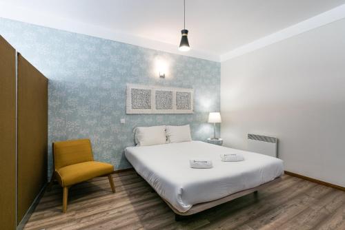 a bedroom with a large bed and a chair at GuestReady - Impulso Aventureiro in Porto