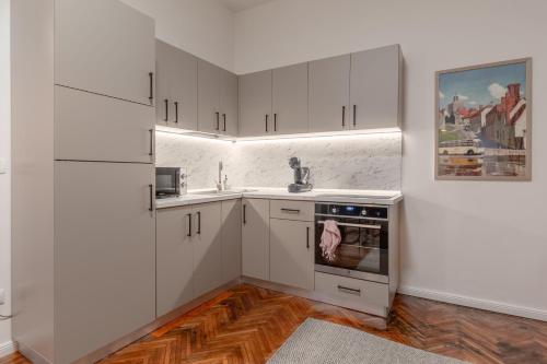 a kitchen with white cabinets and a sink and an oven at Apartament Ultra-Central Premium cu Parcare Gratuita pe Malul Crisului in Oradea