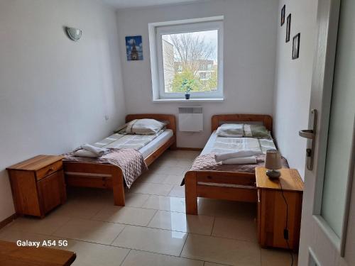 two beds in a room with a window at Apartament z basenem do 8 miejsc noclegowych in Ustronie Morskie