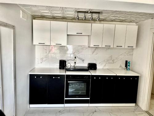 una cocina con armarios en blanco y negro y fregadero en Apartment, en Ryn