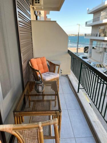 a balcony with two chairs and a table and the ocean at Sea View Apartments near Athens Airport in Artemida