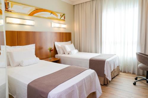 a hotel room with two beds and a window at Bourbon Joinville Convention Hotel in Joinville