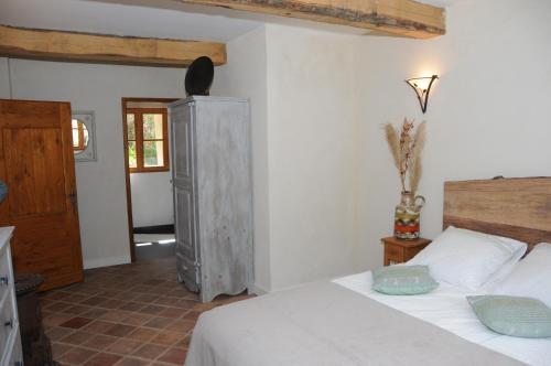 une chambre avec un lit blanc et une armoire en bois dans l'établissement La ferme du Valdeyron, à Valleraugue