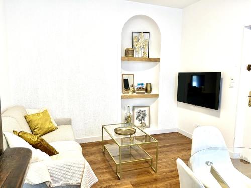 a living room with a white couch and a tv at Les Logis d'Esmeralda-Des appartements au charme intemporel in Romorantin