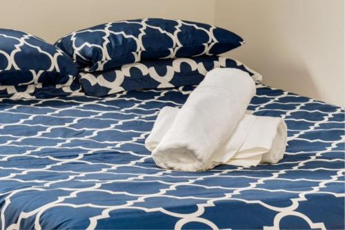 Cama con sábanas y almohadas azules y blancas en Calgary 1 Bedroom Near to Airport Downtown and Shopping, en Calgary