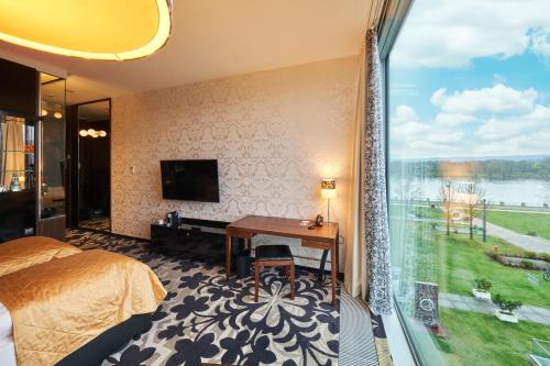 a hotel room with a bed and a large window at Kameha Grand Bonn in Bonn