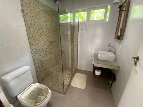 a bathroom with a shower and a toilet and a sink at Dingo - Refugio romântico em meio à natureza in Penedo