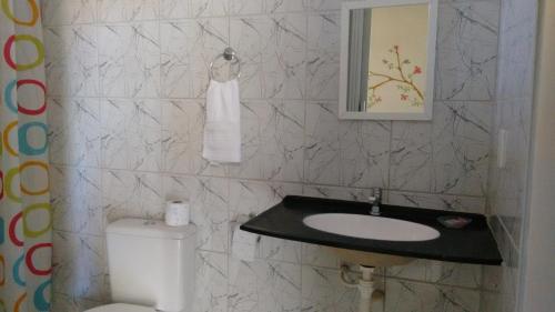 a bathroom with a sink and a toilet and a mirror at Chalés do Otto e Karine in Canoa Quebrada