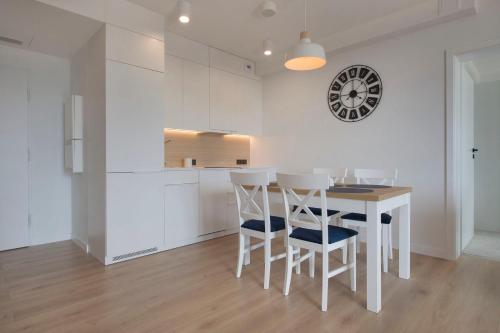 a kitchen with a table and chairs and a clock on the wall at Apartament Superior PINEA 501 in Pobierowo