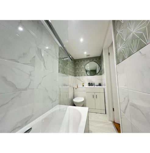 a white bathroom with a tub and a toilet at FB- Spacious 2 Bed Flat Near Edgware Road in London