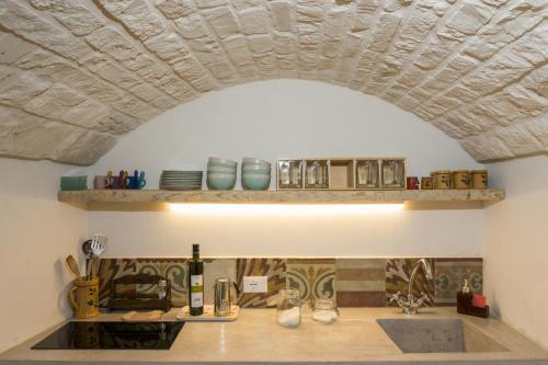a kitchen with an archway over a counter with dishes at Le Dieci Porte in Alberobello