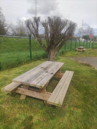 a wooden picnic table in the grass next to a tree at Premiere Classe Vannes in Vannes