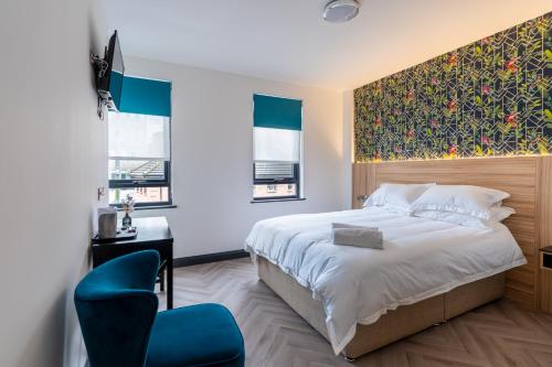 una camera con un grande letto e una sedia blu di Hotel No.9 a Londonderry
